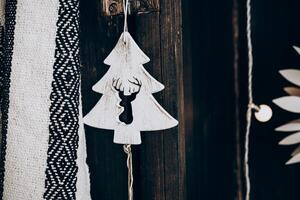 Decorative Christmas ornament shaped like a tree with a deer motif hanging on a wooden background photo