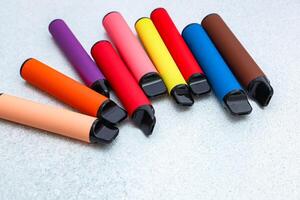 Colorful collection of vape pens arranged on a gray surface in a modern setting photo