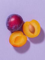 Minimalist flat lay of ripe plum and halved purple fruit on pastel background for summer design photo