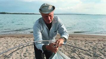 A skilled fisherman prepares his nets at a serene beach with gentle waves video