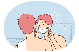 Man shaves face standing in bathroom and looking in mirror doing daily morning hygiene routine vector