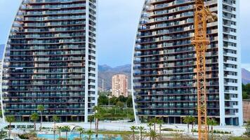 A captivating view of sleek towers currently under construction, featuring a crane against a vibrant urban setting video