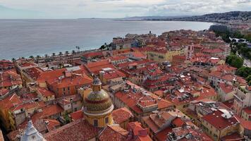 Aerial view of Old Town Nice, France, with red-tiled rooftops, colorful buildings, palm trees, and the dome of Sainte Reparate Cathedral overlooking the Mediterranean Sea on a sunny day. video