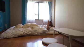 Woman waking up in the japanese style bedroom with futon mattress video
