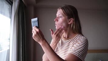 Woman applying cosmetic cream in hotel room looking at the vanity mirror video