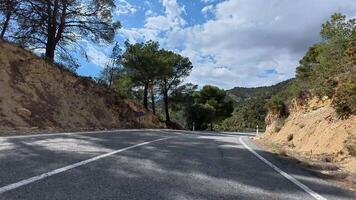 There is a winding mountain road that is beautifully surrounded by lush trees and stunning scenery under a bright sky video