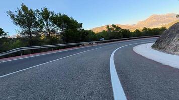 A winding road winds through majestic mountains, lush greenery, and clear blue skies, ideal for adventurers video