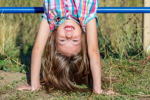 Portrait of smiling caucasian child 7 8 years upside down putting hands on soil photo