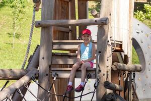 Happy and smiling caucasian child 7 8 years sitting on wood playscape looking at camera photo
