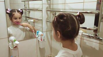 One little girl brushes her teeth in the bathroom in front of the mirror video