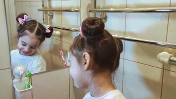 Funny little girl brushes her teeth in the bathroom in front of the mirror video