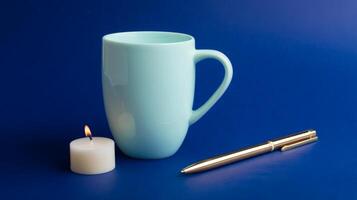 minimal Pastel Mint Mug Candle and Gold Pen on Blue Background photo