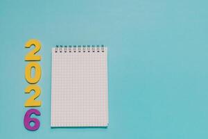 Yellow and purple 2026 next to a blank grid notepad on vibrant blue. Ideal for New Year planning, goal setting, resolutions, and 2026 events. photo