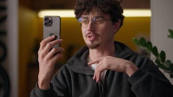 Caucasian guy hipster talking conference holding mobile phone at home freelancer man conversation distant call cellphone communication blogger male speaking influencer recording vlog blogging video