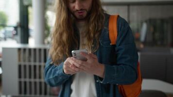 Caucasian student guy man male yelling celebrating winning with mobile phone in university excited screaming victory success achievement betting joyful casino online win in college hallway rejoice video