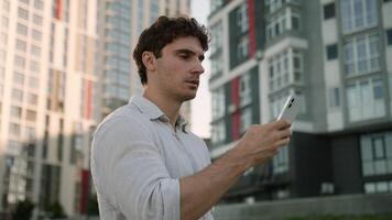 Concentrated Caucasian man business entrepreneur businessman male city employee using mobile phone smartphone guy chatting browsing internet gadget addiction typing message outdoors cellphone screen video