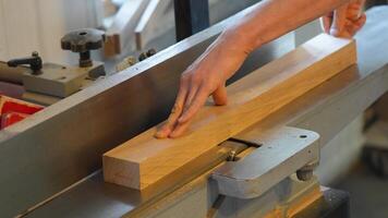 Joiner hands smooth wooden block on electric jointer machine. Man refining surface, woodwork shaping video