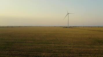 Aerial view of a windmill in rural fields generating renewable energy on a beautiful summer evening. video