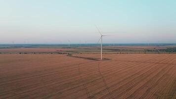 An aerial drone shot of a wind farm producing renewable energy on a summer evening. Due to the weak wind, the blades of the mills rotate very slowly. video