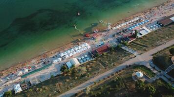 Aerial view of the city beach on a warm summer evening. Sun umbrellas on the yellow sand. People relax and sunbathe on the beach on a summer day by the ocean. video