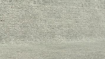 A man is standing on a skateboard in front of a wall video