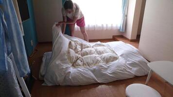 Woman changing bed linens in the japanese style bedroom with white futon mattress video