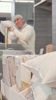Elderly man thoughtfully selecting an orthopedic pillow in a chic furnishings store video