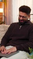 Indian man at home closes laptop angrily, waves hand after internet issue interrupts work. Arabian guy on sofa reacts with visible frustration and disappointment caused by digital connection failure video