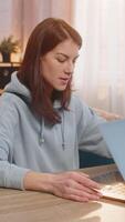 Young woman freelancer closing laptop stretches back and looks joyfully at the camera signaling the successful end of workday and readiness to relax. Caucasian girl showing thumbs up sitting at table. video
