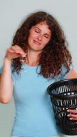 Woman dramatically taking off glasses and throwing them into trash, humorous gesture expressing rejection. Girl on gray background playfully shows funny disappointment, ironic negative emotional mood. video