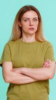 Middle-aged woman crosses arms and gives strict serious look, expressing disagreement, refusal or denial with firm body language. Girl isolated on blue background shows rejection or strong disapproval video