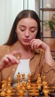 Young woman at home table studies chessboard and moves pieces alone thinking deeply and planning strategy. Caucasian girl enjoys mental challenge and tests patience through silent tactical play. video