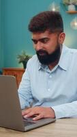 Indian man at home reads email reply on laptop smiles nods satisfied project finished success achieved. Arabian guy at table feels confident celebrates outcome sets new goals forward progress today. video