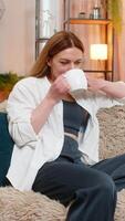 Middle-aged woman enjoys drinking warm tea at home in the morning, sitting quietly in peaceful mood. Happy adult girl feels calm and grounded, embracing slow start of day with comfort and clarity. video
