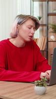 Young woman tiredly closing laptop sitting at home table, holding head demonstrating severe headache after long work. Caucasian girl exhausted, showing discomfort and pain from remote work fatigue. video