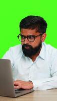 Indian man looks at laptop with frustrated or sad expression reacting to failure bad news or lost opportunity. Hispanic guy isolated on green chroma key background showing defeat and emotional letdown video