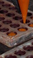 Chocolatier skillfully piping vibrant fruit cream into chocolate molds video