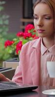 Stylish young woman sipping coffee while browsing the Internet at a cozy cafe video