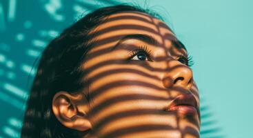 woman gazes upwards shadowed by vertical sunlight stripes. photo