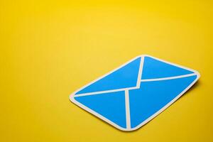 Paper letter on yellow background, with copy space. Business concepts of online contact channels, electronic mail inbox notifications, and sending and receiving documents using online networks. photo