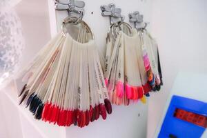 A row of nail polish bottles are hanging on a wall photo