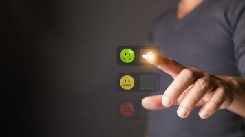 A man touch the icon on the happy smile face to indicate satisfaction with the service. Feedback, survey, and review concept. Rating Very impressed. photo