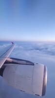 Airplane turbine panning over fluffy cloud layer with glowing sunset colors surrounding wing during scenic aerial flight journey. video