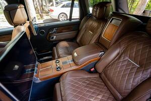 The luxurious brown leather interior of a highend SUV features an array of stylish design elements that elevate the overall ambiance and create an exclusive, sophisticated environment for travel photo