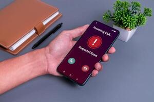 Spammer incoming call concept. Hand holding smartphone with incoming call from unknown caller on phone screen. photo