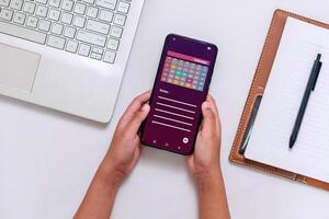 Hands holding a smartphone with calendar app on screen to check schedule, reminder or appointment photo