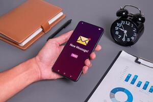 A businessman at his desk receives a new message, email notification or social media notification on his smartphone. photo