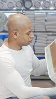 Stylish man evaluating orthopedic mattress sample in vibrant furniture store video