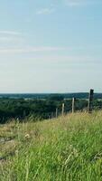 A fence and grassy hill with a view of the countryside video