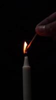 A person is seen igniting a white candle using a matchstick in a darkened environment, capturing a moment of illumination and atmosphere creation. video